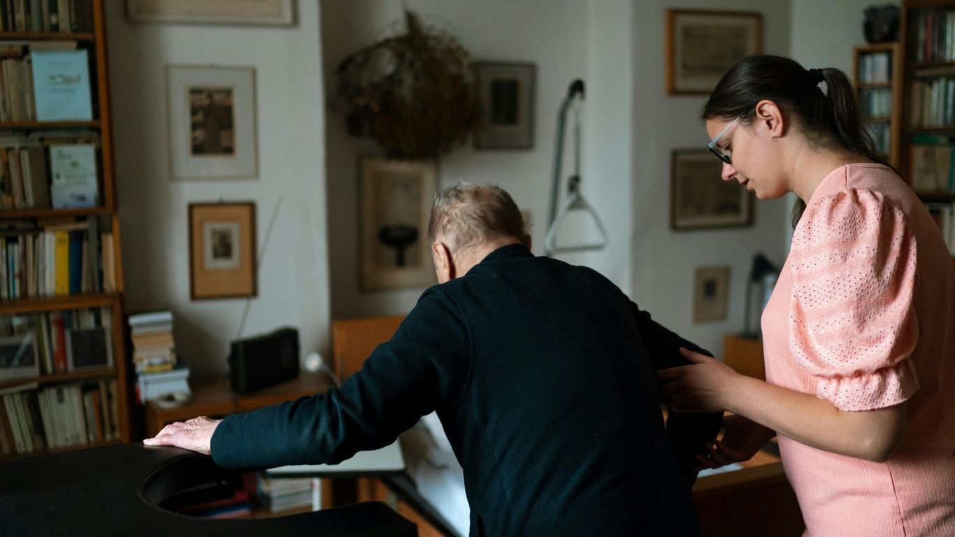 A support worker alongside a person playing the piano at home