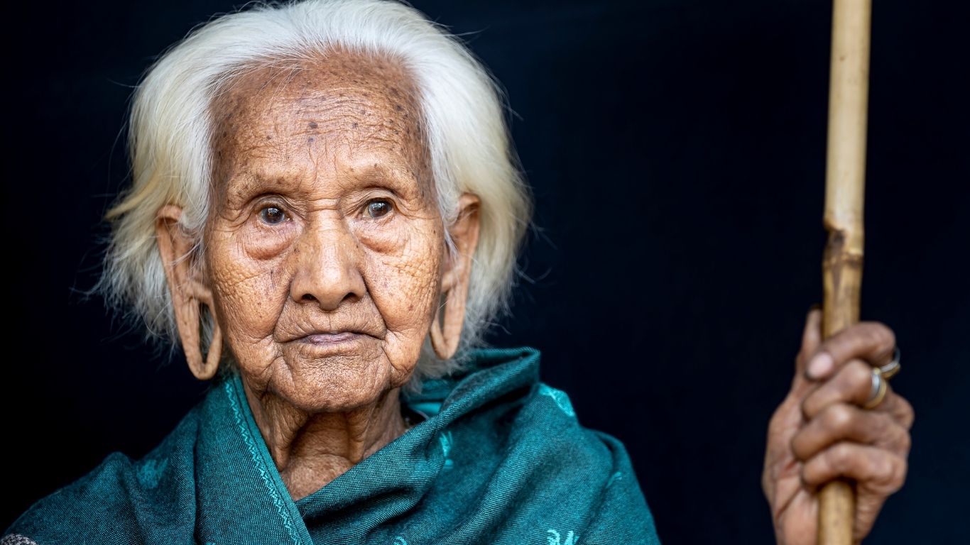 An older woman wrapped in a teal shawl