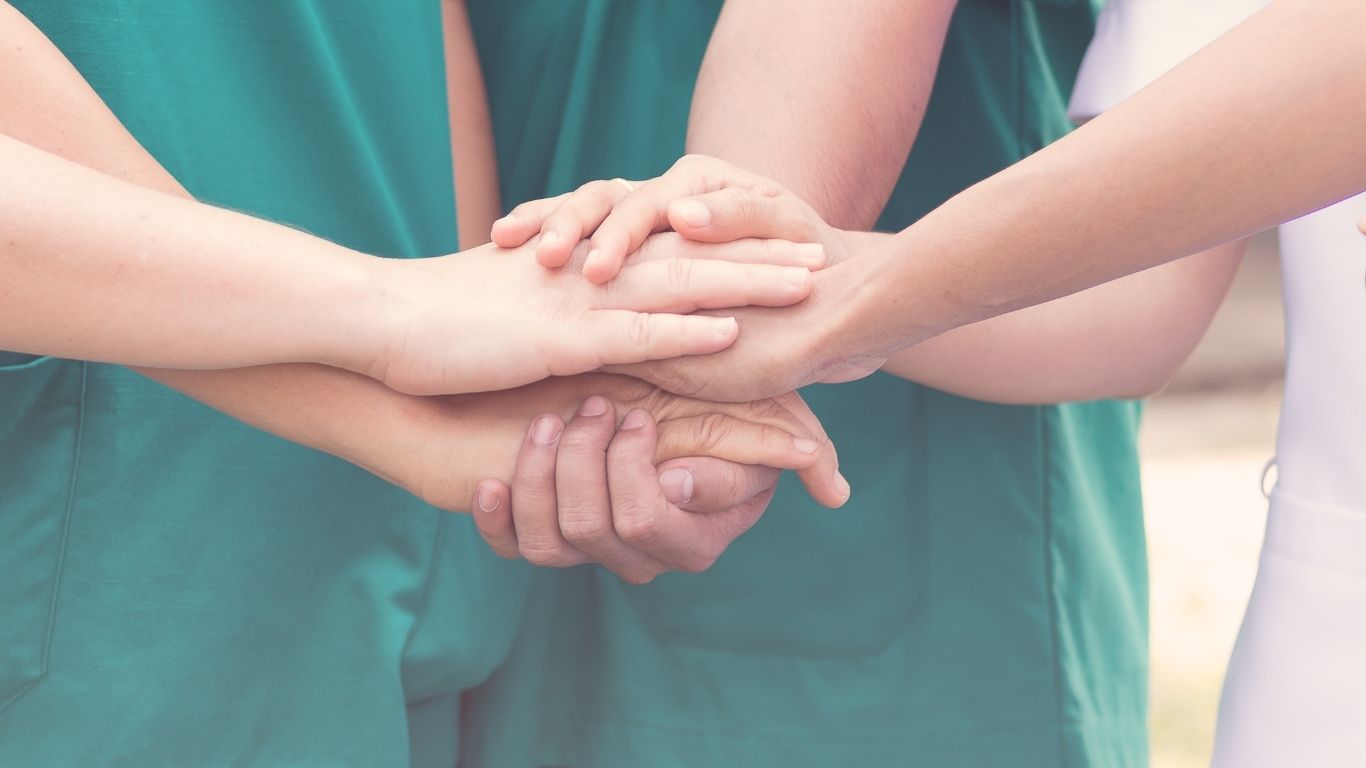 Healthcare professionals joining hands in support