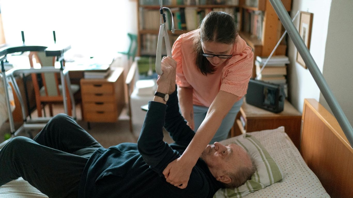 A care professional assisting a person with movement in a care setting